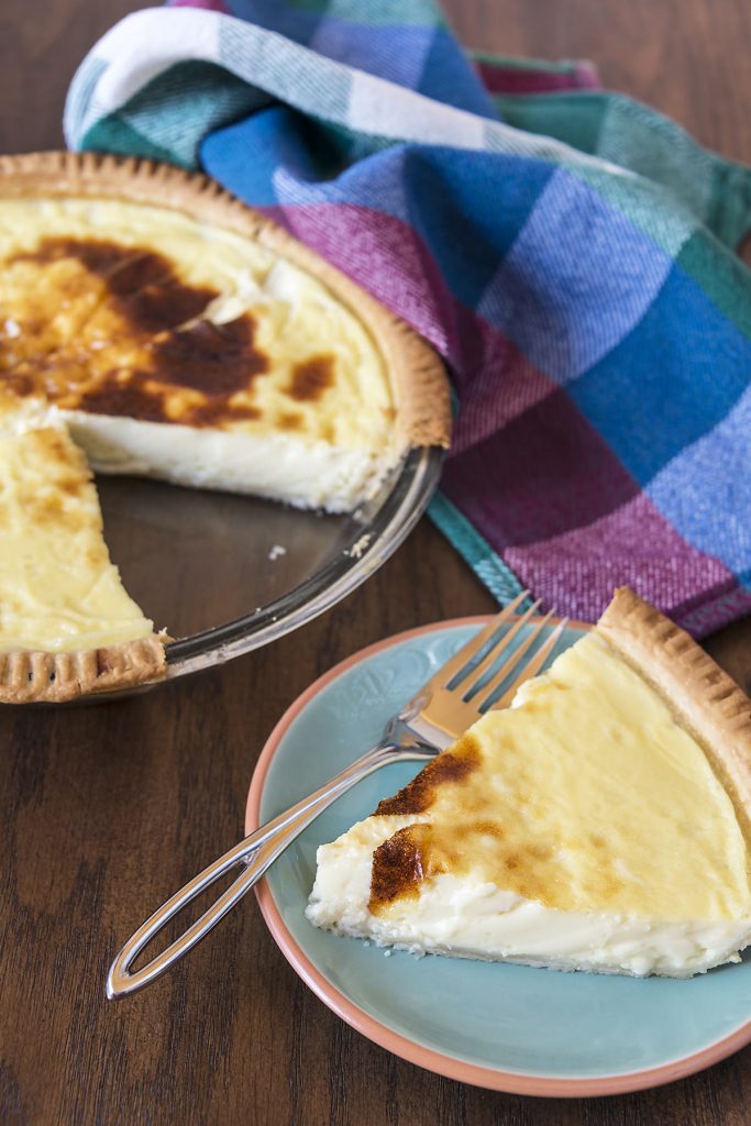 A delicious slice of pie has been cut from a fresh baked custard pie.